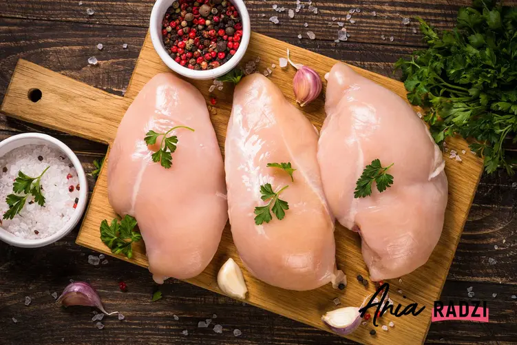 Surowa pierś z kurczaka na desce oraz porady, jak ugotować pierś z kurczaka w wodzie lub w wywarze warzywnym