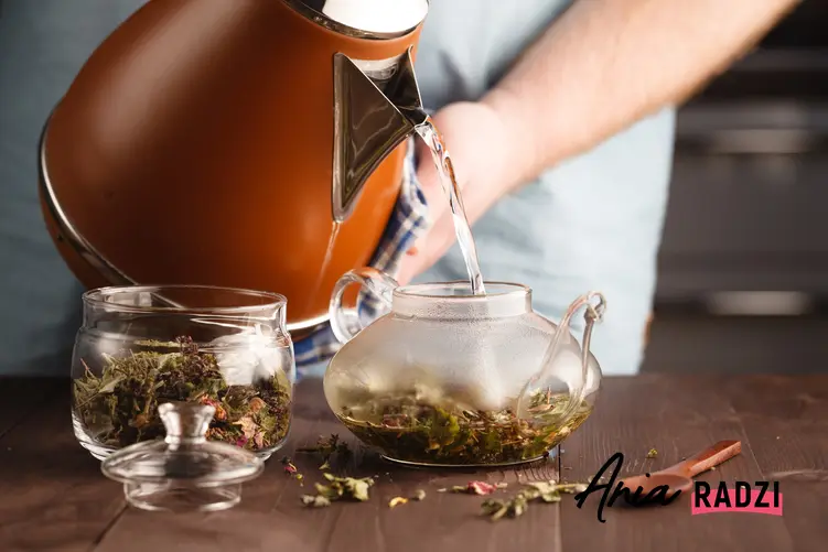 Mężczyzna podczas parzenia herbaty ziołowej, a także porady, jak pozbyć się wody z organizmu
