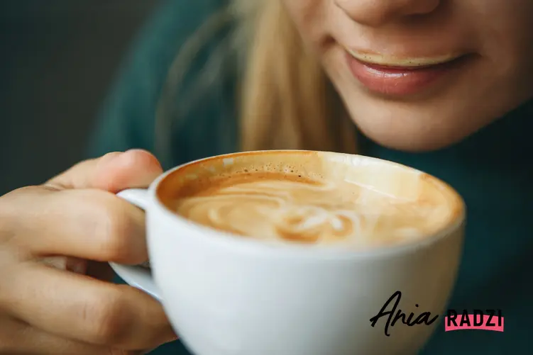 Kobieta pijąca kawę z pianką z filiżanki oraz porady, jak spienić mleko domowymi sposobami