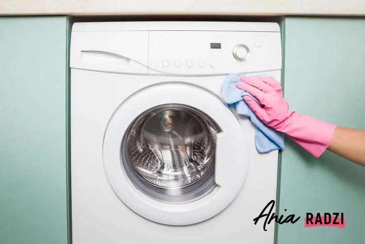 Pani w różowej rękawiczce wyciera szmatką pralkę, 5 zasad czyszczenia wnętrza pralki, środki do czyszczenia brudnej pralki