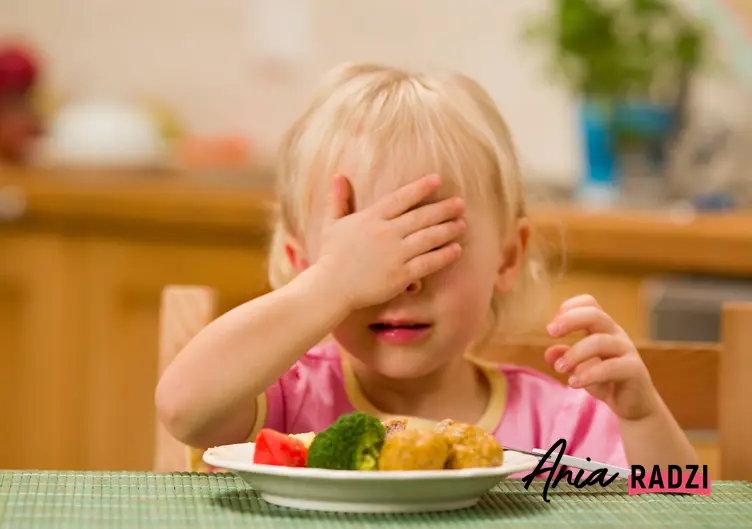 Dziecko zasłaniające oczy przed talerzem z obiadem, a także polecane przepisy na obiad dla dzieci