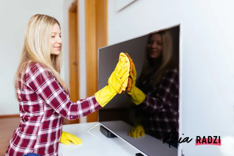 Kobieta, która czyści ekran telewizora plazmowego oraz porady, jak i jakim środkiem umyć ekran telewizora LED