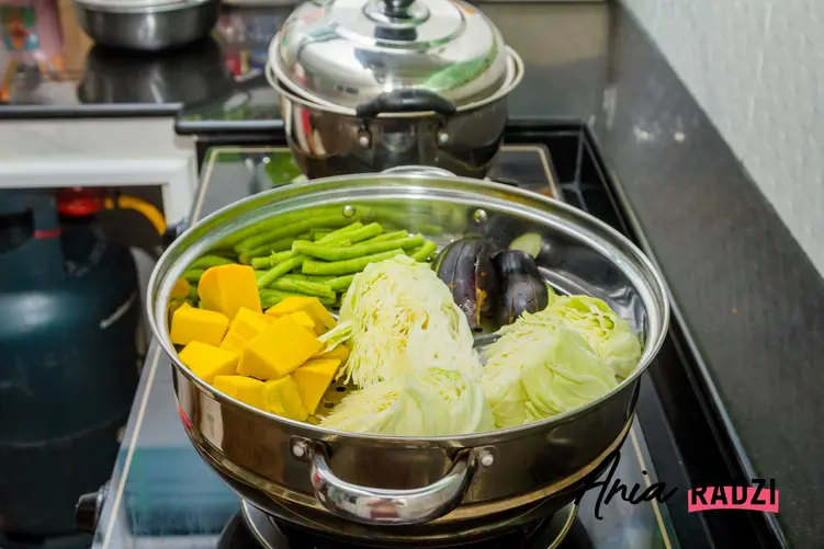 Warzywa gotowane na parze oraz garnek do gotowania na parze lub inne naczynie do gotowania na parze na kuchenkę gazową