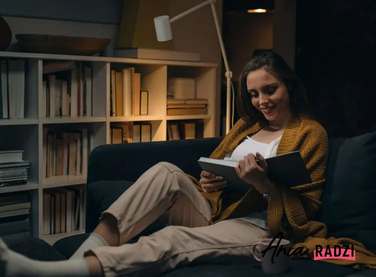 Kobieta czytająca ksiązkę na kanapie i pijąca herbatę oraz sposoby na Dzień Kobiet