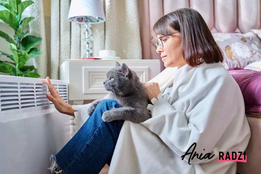 kobieta okryta kocem dotyka grzejnika