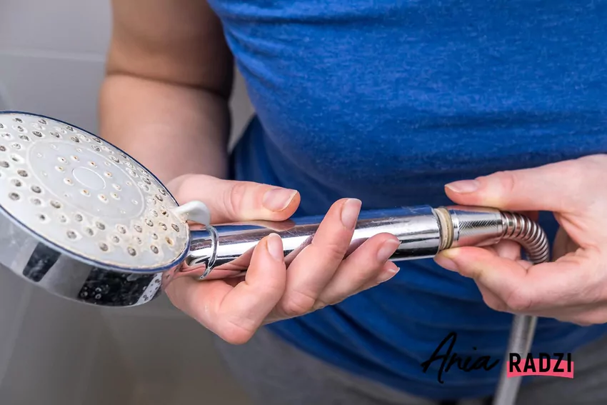 Kobieta trzyma słuchawkę prysznica