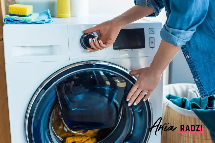 Kobieta włącza pralkę w domu