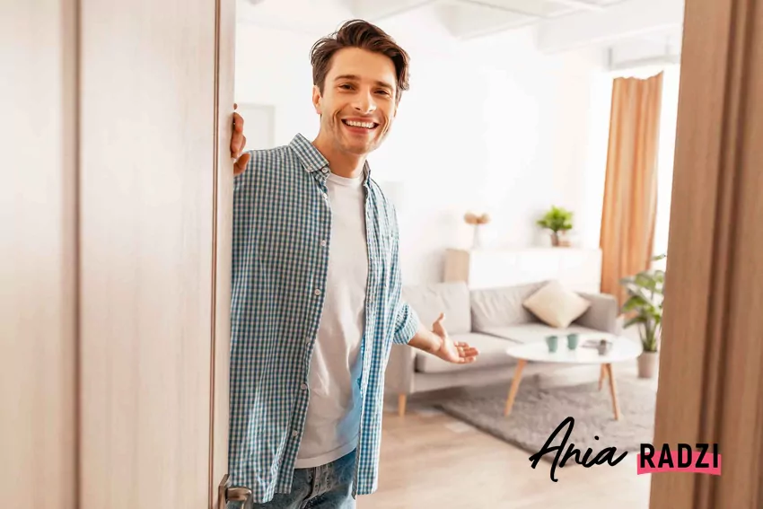 Najczęściej popełniane błędy w aranżacji niedużego mieszkania Mężczyzna zapraszający do mieszkania, błędy w urządzaniu małego mieszkania