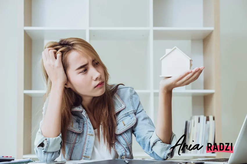 smutna kobieta patrzy na miniaturowy dom