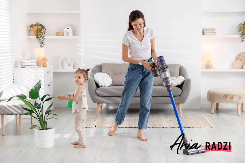 Zatrudnienie sprzątaczki to nie powód do wstydu Młoda kobieta sprząta pokój, obok stoi mała dziewczynka
