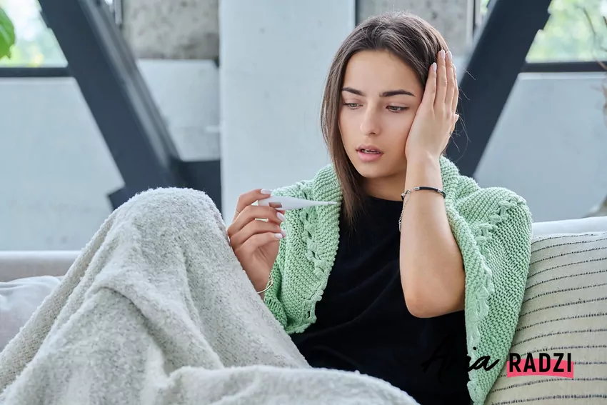 Zbyt wysoka temperatura w domu może prowadzić do osłabienia naturalnej odporności Chora kobieta spogląda na termometr