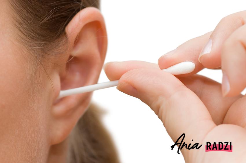 Kobieta czyszcząca ucho przy pomocy patyczka do uszu oraz porady, czym czyścić uszy