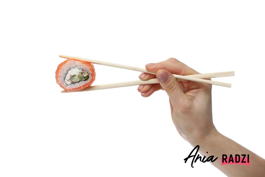 Trzymanie pałeczek do sushi na białym tle oraz porady, jak trzymać pałeczki do sushi