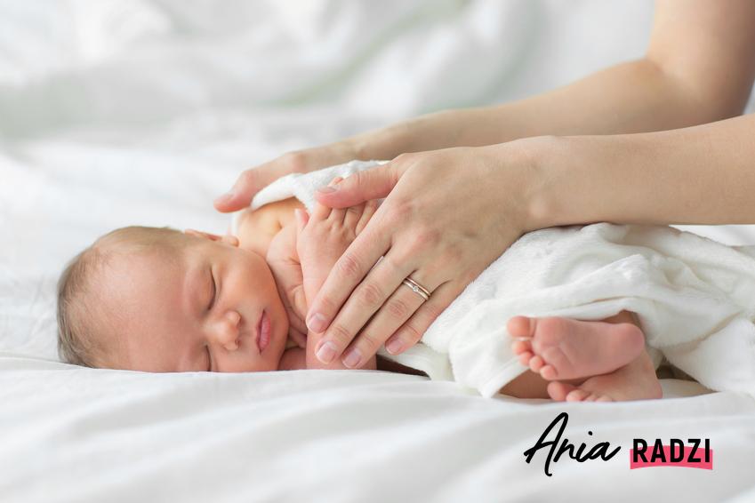 Śpiący noworodek trzymany przez mamę, a także co na czkawkę u noworodka