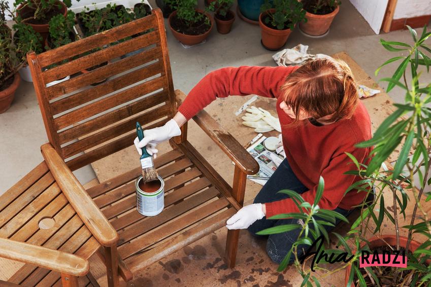 Kobieta malująca drewniane meble ogrodowe oraz czym malować drewno, jak pomalować drewno