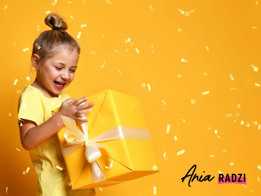 Dziewczynka ciesząca się z prezentu, a także oryginalne prezenty na dzień dziecka, najlepsze propozycje