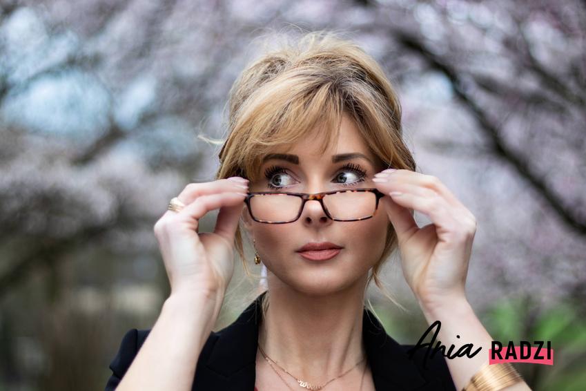 Kobieta ściągająca okulary w grubych oprawkach, a także najmodniejsze 8 oprawek okularów damskich