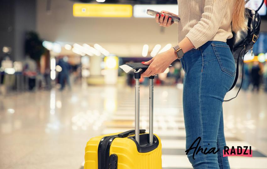 Kobieta z walizką na lotnisku, a także co zrobić, jeśli walizka na lotnisku zostanie zniszczona krok po kroku