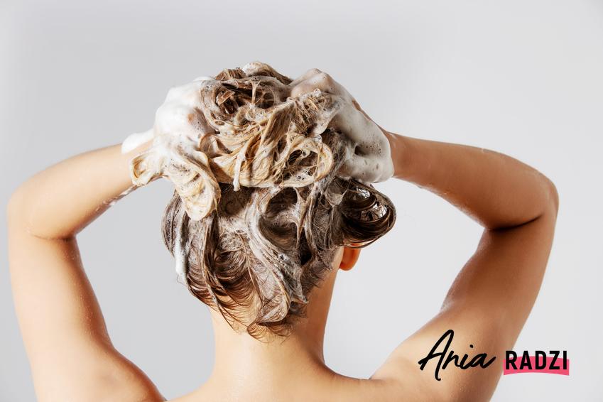 Kobieta podczas mycia włosów pod prysznicem, a także porady, jak działa proszek do pieczenia na włosy przetłuszczające się