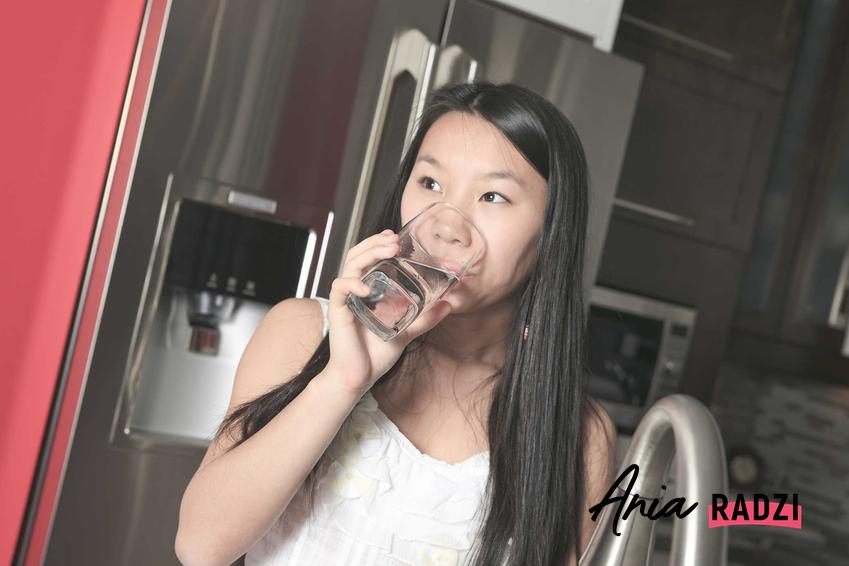 Dziewczyna pijąca przefiltrowaną wodę z lodówki oraz polecany filtr do lodówki Samsung typu side by side