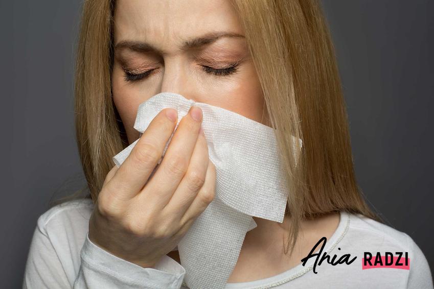 Kobieta z katarem wydmuchująca nos, czyli domowe sposoby na katar i leczenie kataru domowymi sposobam