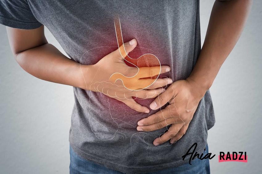 Mężczyzna trzymający dłonie na żołądku oraz domowe sposoby na ból żołądka i porady, co zrobić jak boli żołądek