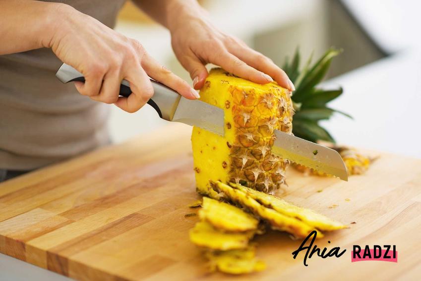 Kobieta podczas obierania ananasa oraz porady, jak obrać ananasa krok po kroku i jak usunąć skórę z ananasa